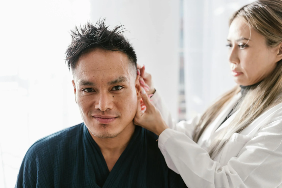 a-woman-in-white-laboratory-gown-looking-at-a-mans-ear