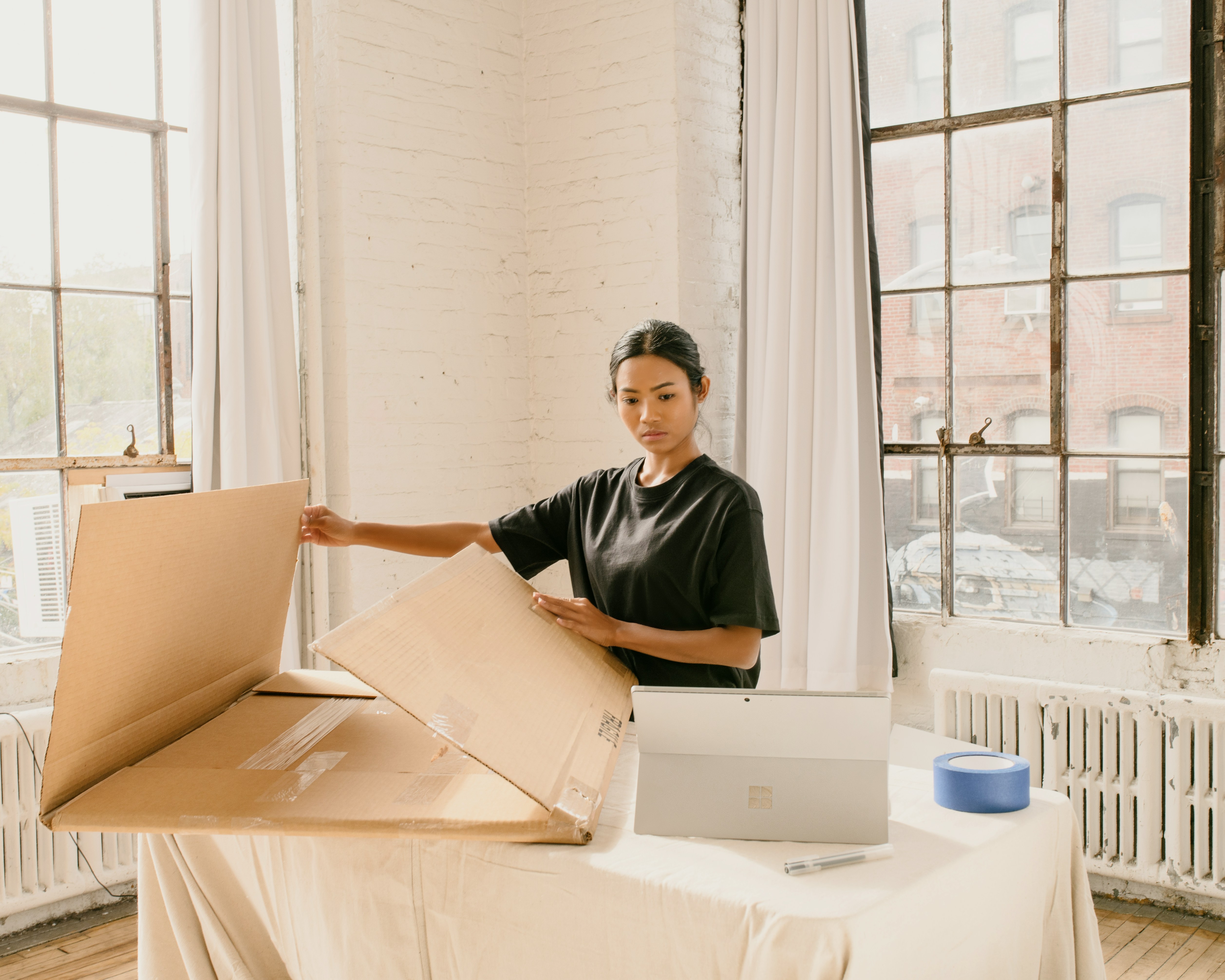 a-woman-standing-next-to-a-cardboard-box-on-top-of-a-table