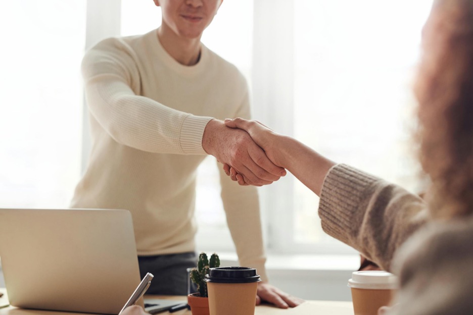 Man-standing-at-table-shaking-hands-with-woman