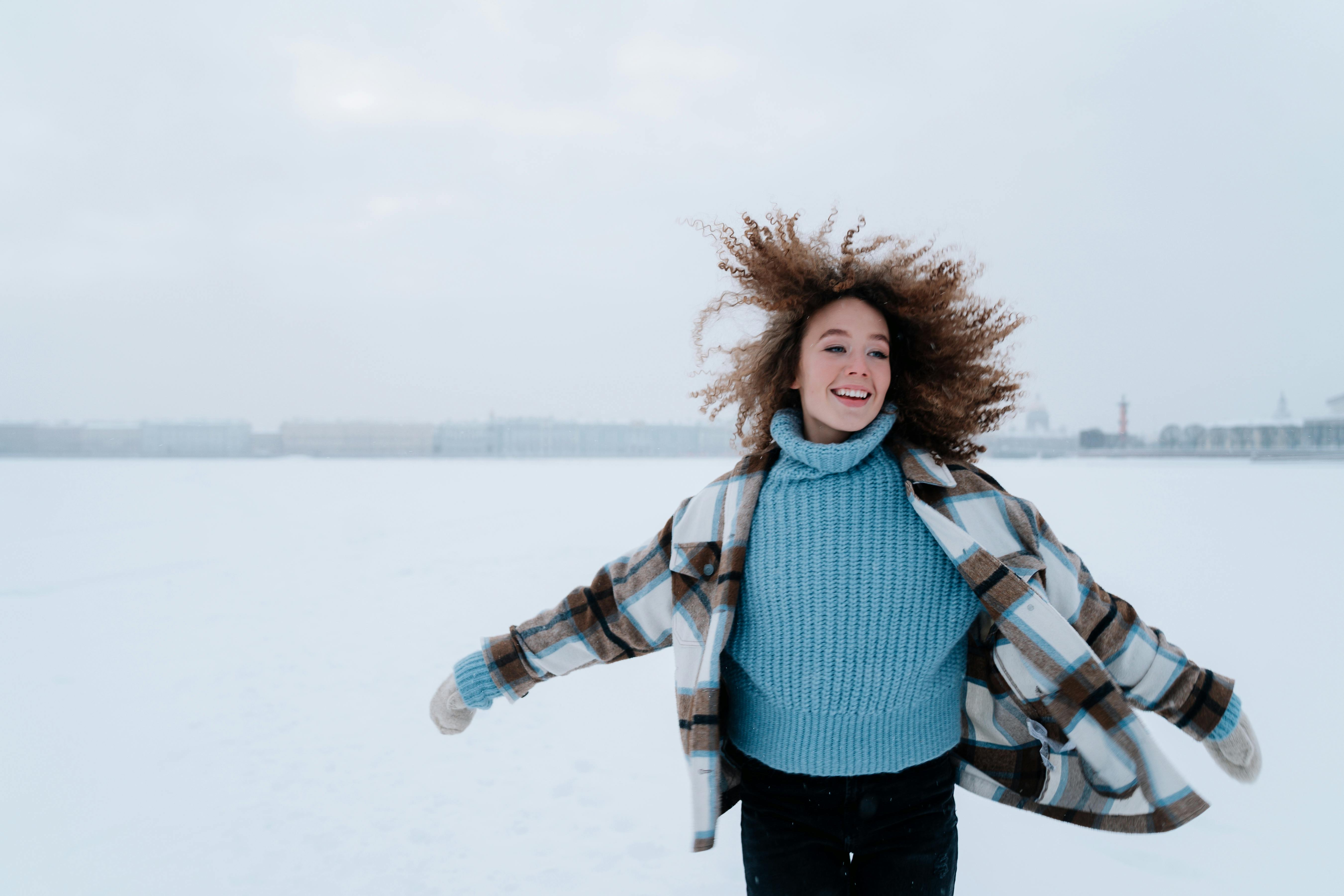 woman-with-curly-hair-running-through-snow-field