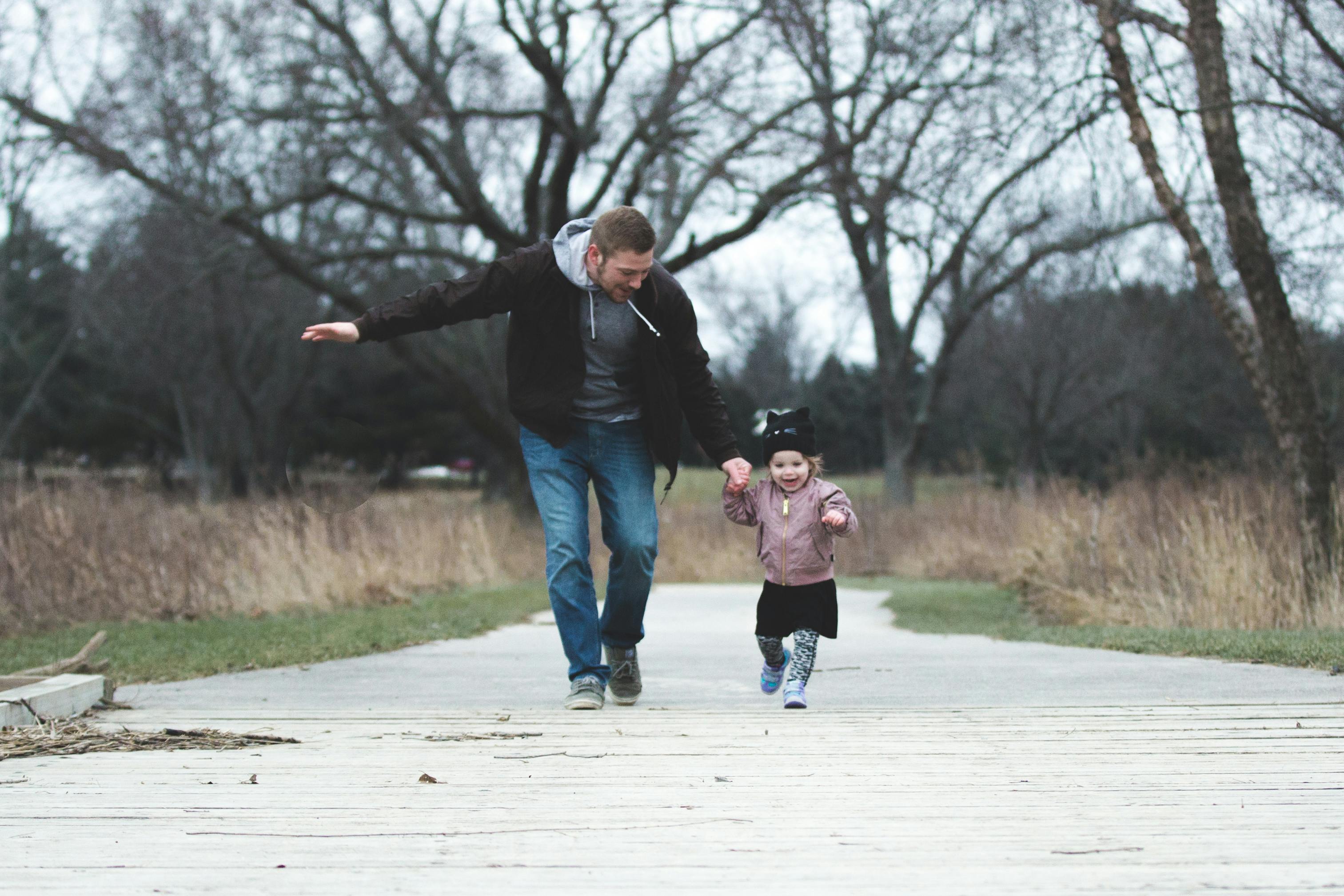 a-father-and-his-little-girl-running-on-a-park-pathway